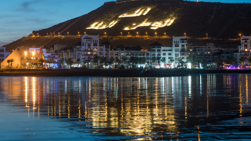 Vue nocturne animée d'Agadir avec des lumières scintillantes et des discothèques.