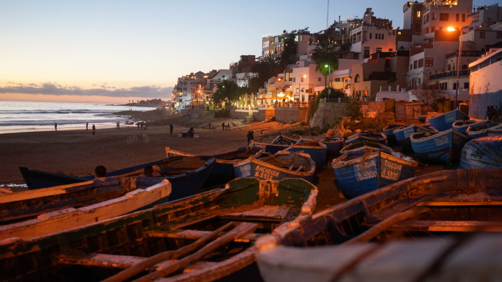 une vue pittoresque du village éclairé par les lumières avec l'océan en arrière-plan, mettant en valeur son atmosphère détendue et ses charmes côtiers.